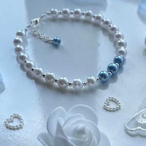 May include: A white and blue pearl bracelet with a silver clasp. The bracelet has a gradient of blue pearls at one end.