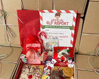 May include: A Christmas gift box containing an Official Elf Report card, a red organza bag with a key, a candy cane, a bag of sweets, a chocolate bar with a Santa illustration, a bag of reindeer food, chocolate coins, and a snowman cutout.
