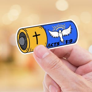 May include: A sticker in the shape of a battery, held by a hand. The sticker is yellow and blue with a cross and a dove, and the text "ACTS 1:8".