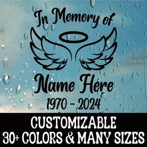 May include: A black vinyl decal featuring the text In Memory of, Name Here, and the years 1970-2024. The design includes a pair of stylized angel wings and a halo centered between the text lines. The decal is displayed on a glass surface.