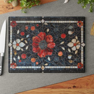 Peut inclure: Une planche à découper en verre avec un motif en mosaïque représentant des fleurs rouges et blanches sur un fond bleu foncé.