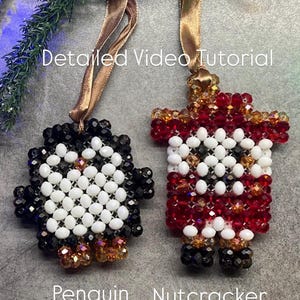Puede incluir: Dos adornos navideños de cuentas: un pingüino y un cascanueces. El pingüino es negro, blanco y dorado. El cascanueces es rojo, blanco, dorado y negro. Ambos tienen cintas doradas. El texto de la imagen dice "Detailed Video Tutorial", "Penguin Nutcracker".