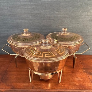 Puede incluir: Tres platos de servir dorados con diseños geométricos verdes y dorados. Los platos están sobre soportes individuales con un acabado dorado.