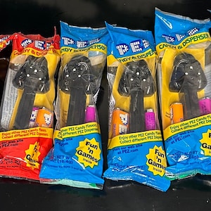 Può includere: Otto dispenser PEZ di Star Wars Darth Vader confezionati singolarmente. Ogni confezione è blu, rossa o gialla e presenta il testo "Fun 'n Games" e "PEZ Candy & Dispenser".