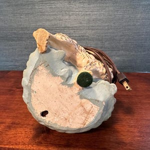 Puede incluir: Una base de l&aacute;mpara de cer&aacute;mica con una figurita de perro blanco y marr&oacute;n. La base es de color azul claro y tiene un cable con un enchufe.
