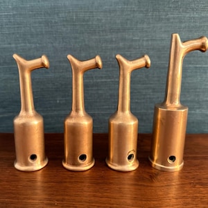 Puede incluir: Cuatro herramientas de latón con puntas de diferentes formas. Las herramientas son todas del mismo tamaño y tienen un cuerpo cilíndrico.
