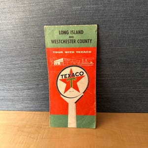 Peut inclure: Guide de voyage vintage pour Long Island et le comté de Westchester. La couverture rouge et verte présente le logo Texaco, une main blanche tenant une étoile rouge et le texte "TOUR WITH TEXACO".