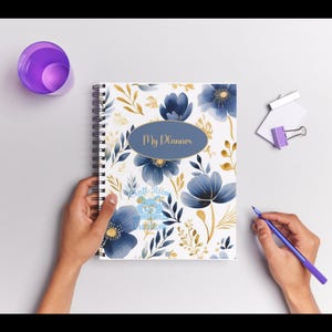 May include: A white spiral bound planner with a blue and gold floral design. The cover features the text "My Planner" in a gold oval.