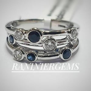Op de afbeelding: Een zilveren ring met drie banden met afwisselend blauwe saffieren en heldere diamanten. De ring is bezet met bezel-gezet stenen.
