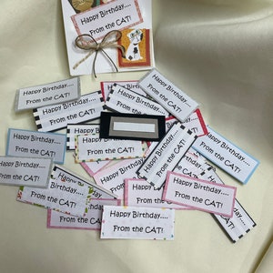 May include: A collection of colorful cards with the text "Happy Birthday... From the CAT!" printed on them. The cards are decorated with various patterns and designs, including stripes, polka dots, and flowers.