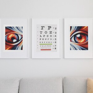 May include: Three framed prints on a white wall above a gray sectional sofa. The center print is a black and white eye chart with the letters "FP" at the top. The left and right prints are abstract images of a red eye with orange and blue swirls.