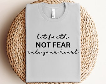 Puede incluir: Una camiseta gris con el texto "let faith NOT FEAR rule your heart" impreso en negro.