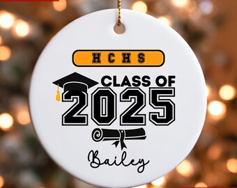 May include: White ceramic ornament with a black graduation cap, diploma, and the text "Class of 2025" in black. The text "HCHS" is in orange on a black rectangle. The name "Bailey" is written in cursive below the graduation cap.