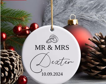 Könnte beinhalten: Weißer Keramik-Weihnachtsbaumschmuck mit schwarzem Text "MR & MRS Dexter 10.09.2024" und einer Zeichnung von zwei ineinander verschlungenen Ringen.