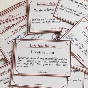 Puede incluir: Un conjunto de tarjetas color crema con bordes y texto burdeos. Las tarjetas presentan frases como "Life Skills", "Anti-Rot Rituals" y "Romanticize Your Life". Las tarjetas están diseñadas para inspirar y fomentar el autocuidado.