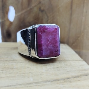 May include: A silver ring with a large, rectangular, deep pink gemstone.