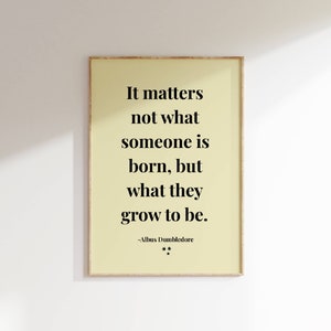 May include: Framed print with a light yellow background and black text. The quote reads "It matters not what someone is born, but what they grow to be." by Albus Dumbledore. Two small stars are below the quote.