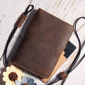 May include: A brown leather notebook cover with a black strap and a clasp. The cover has a flap with a small pocket and the word "YOU" embossed on the front.