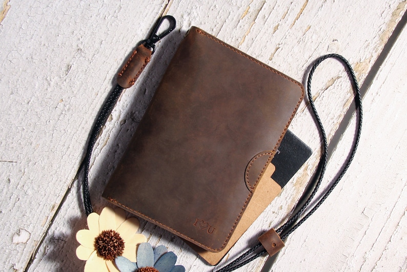 May include: A brown leather notebook cover with a black strap and a clasp. The cover has a flap with a small pocket and the word "YOU" embossed on the front.