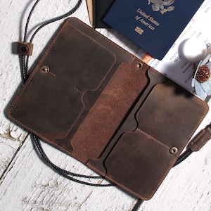 May include: A brown leather wallet with multiple card slots and a strap. The wallet is open and has a passport and boarding pass inside.