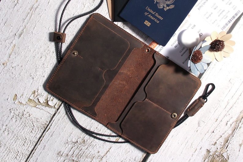 May include: A brown leather wallet with multiple card slots and a strap. The wallet is open and has a passport and boarding pass inside.
