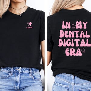 May include: Black t-shirt with a pink tooth graphic and the text "In My Dental Digital Era" on the back. The front of the shirt has a pink tooth graphic and the text "Lauren".