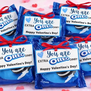 Puede incluir: Varios paquetes de galletas Oreo azules atados con lazos rojos. Cada paquete tiene una etiqueta blanca que dice "You are EXTRA OREO DINRY Happy Valentine's Day!" con un corazón azul.