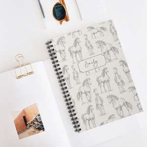 May include: A white spiral notebook with a grey horse pattern and the name "Emily" printed on the cover.