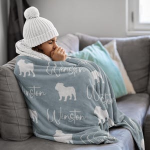 Personalized English Bulldog blanket in pale blue with white english bulldog silhouettes and custom name, soft fleece throw for sofa or bed.