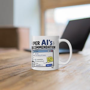Op de afbeelding: Witte keramische mok met de tekst "PER AI'S RECOMMENDATION" en een mock e-mail ontwerp. De e-mail luidt "Gewoon AI-richtlijnen volgen" en bevat een plakbriefje met de tekst "AI ZEI STUUR HET". Een laptop is zichtbaar op de achtergrond.