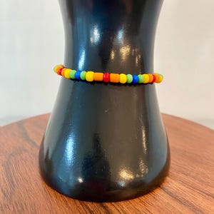May include: A colorful beaded bracelet with red, orange, yellow, green, and blue beads.