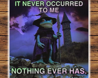 May include: A green frog wearing a purple robe and a pointed hat stands in front of a stone tower. The text "IT NEVER OCCURRED TO ME" is above the frog and "NOTHING EVER HAS." is below the frog.