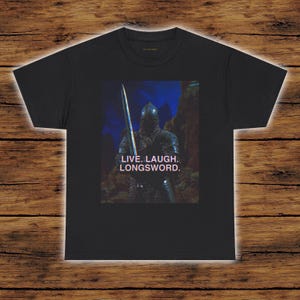 May include: Black t-shirt featuring a graphic of a knight in armor holding a longsword. The image includes the text "LIVE. LAUGH. LONGSWORD."