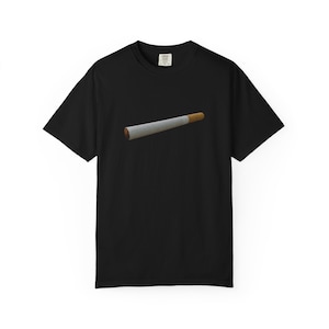 May include: A black short-sleeve t-shirt featuring a centered graphic of a single cigarette. The cigarette is depicted with a white paper body and a tan filter tip, positioned horizontally across the chest area of the solid black garment.