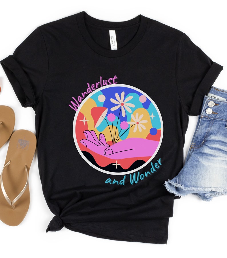 May include: Black t-shirt with a colorful graphic of a hand holding flowers in a circle. The text "Wanderlust and Wonder" is written below the graphic.