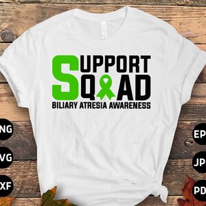 Op de afbeelding: Wit T-shirt met een groen lint en de tekst "Support Squad Biliary Atresia Awareness".