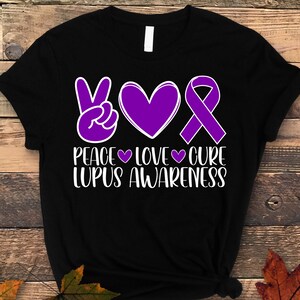May include: Black t-shirt with a purple peace sign, heart, and ribbon. The text "Peace Love Cure Lupus Awareness" is printed in white.
