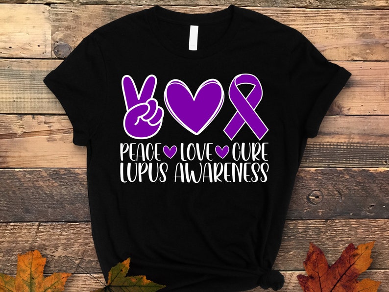 May include: Black t-shirt with a purple peace sign, heart, and ribbon. The text "Peace Love Cure Lupus Awareness" is printed in white.