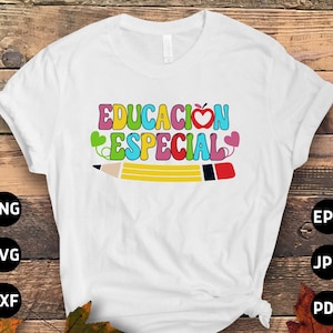 以下が含まれることがあります： カラフルな文字で「EDUCACION ESPECIAL」と書かれた白いTシャツ。赤いハートのリンゴと赤い消しゴムのついた黄色の鉛筆が描かれている。