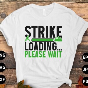 Peut inclure: T-shirt blanc avec du texte noir qui dit "Strike Loading... Please Wait". Un graphique de quille de bowling vert est à côté du texte. Le t-shirt est sur un fond en bois.