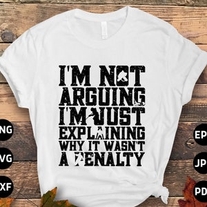 Peut inclure: T-shirt blanc avec un texte noir qui dit "Je ne suis pas en train de me disputer, je suis juste en train d'expliquer pourquoi ce n'était pas une pénalité". Le texte a un aspect vieilli. Le t-shirt est sur un fond en bois avec des feuilles d'automne.