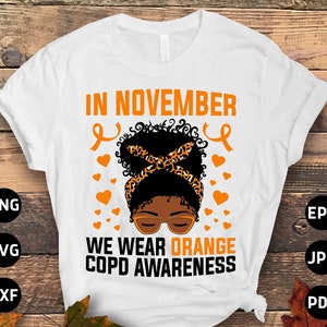 May include: White t-shirt with the text "IN NOVEMBER WE WEAR ORANGE COPD AWARENESS". The design includes an illustration of a woman with a leopard print headband, orange hearts, and ribbons.