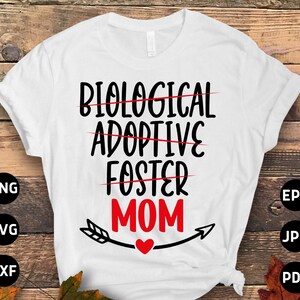 Op de afbeelding: Wit T-shirt met zwarte tekst die "Biologisch, Adoptief, Foster, Moeder" luidt met een rood hart en een pijl. De woorden "Biologisch", "Adoptief" en "Foster" zijn doorgestreept.