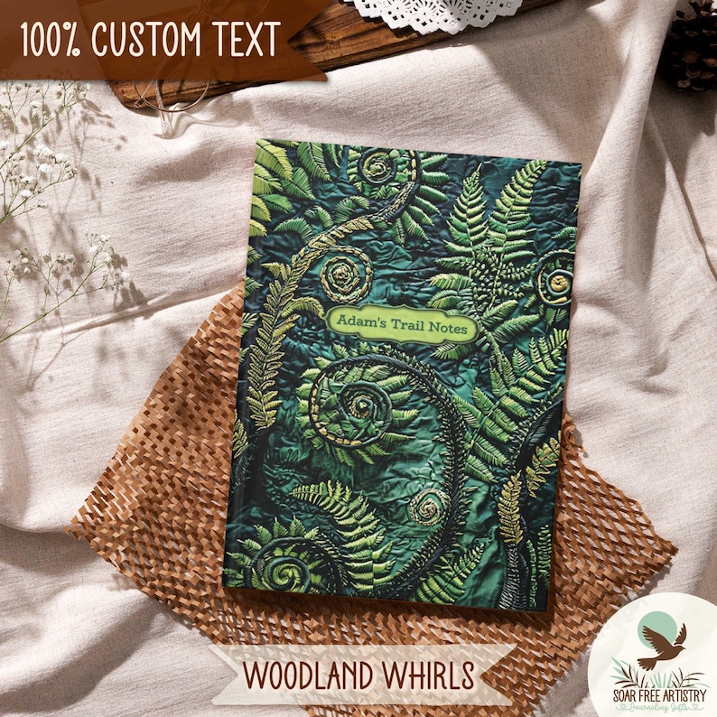 2 of 5 Forest aesthetic journal gifts for hikers, her or him. This woodland notebooks is called Woodland Whirls and is one of my most popular forest journals and is displayed on a beige outdoor picnic blanket. A rustic forest green nature journal is perfect for family camping memories, hiking adventures and forest lovers.