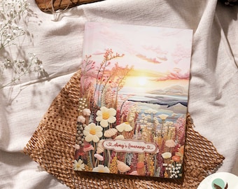 May include: A pink and orange sunset over a body of water with a field of flowers in the foreground. The flowers are white, pink, and yellow. The text "Amy's Journey" is written in a heart-shaped frame.