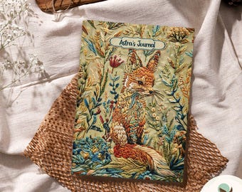 May include: A journal cover with a colorful embroidered design featuring a fox surrounded by flowers and foliage. The title "Astra's Journal" is printed on the cover.