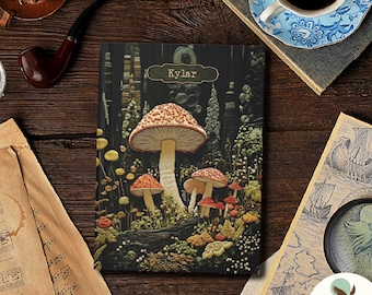 May include: A custom notebook with a mushroom forest design. The cover features a large mushroom with a red and white spotted cap, surrounded by smaller mushrooms and foliage. The name "Kylar" is printed at the top. The text "100% CUSTOM TEXT" is at the top left.