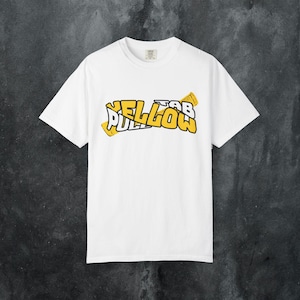 Puede incluir: Camiseta blanca con un diseño amarillo y negro que dice "Yellow Tab Pillow". El diseño presenta una fuente estilizada con una estética lúdica y de dibujos animados. La camiseta es de estilo cuello redondo clásico.