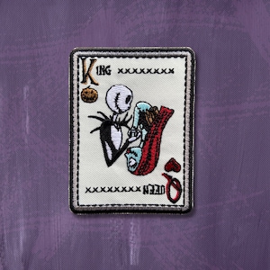 May include: A white playing card with a black border. The card is a King of Hearts and features a cartoon image of Jack Skellington from the Nightmare Before Christmas. The card has the text "KING" in the top left corner.