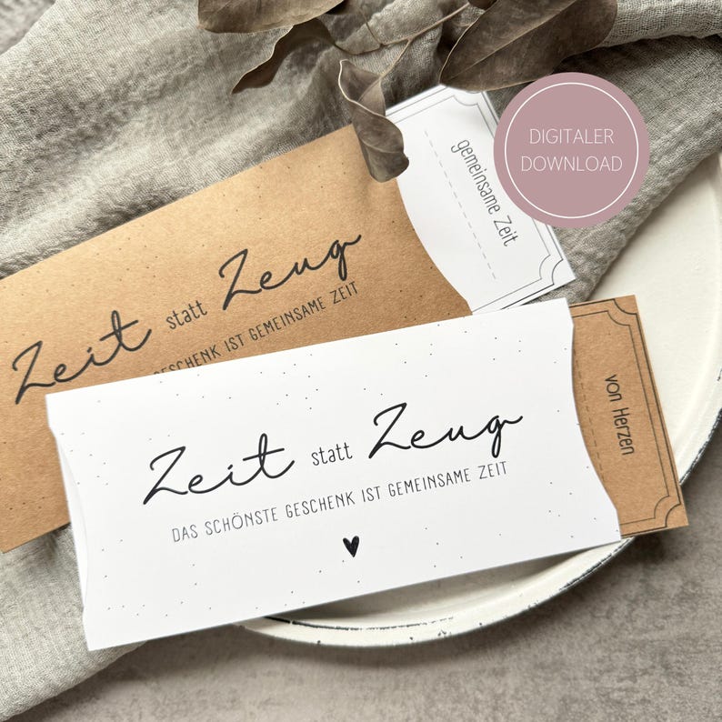 May include: Two gift card holders, one brown and one white, with black script that reads "Zeit statt Zeug" and "Das Sch&ouml;nste Geschenk ist gemeinsame Zeit." A small heart is visible on the white card. A pink circle reads "DIGITALER DOWNLOAD."